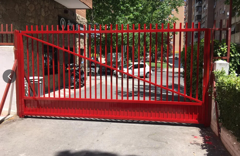 Puerta metálica corredera roja para acceso de vehículos en urbanización de Murcia